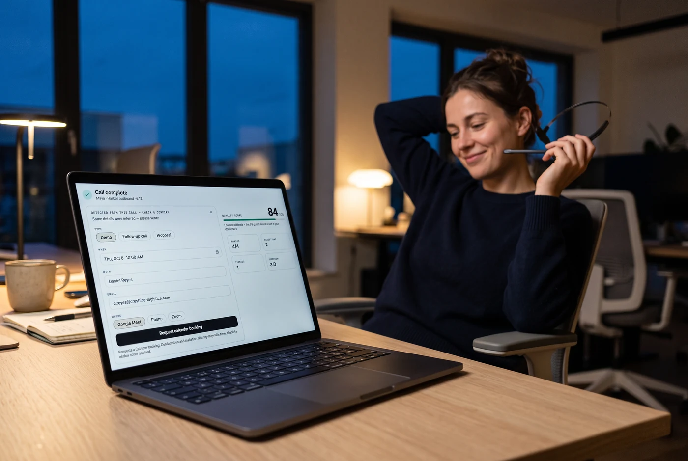 A rep leaning back with her headset in her hand; the laptop in front of her shows a DealPrompt call summary with a quality score of 84